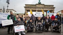 Foto: Auf einer Demonstration vor dem Brandenburger Tor in Berlin halten Demonstranten Plakate mit der Aufschrift: "Teilhabe statt Ausgrenzung" hoch; Copyright: Jörg Farys | Gesellschaftsbilder.de